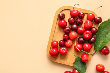 Board with sweet cherries on beige background
