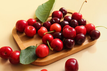 Board with sweet cherries on beige background