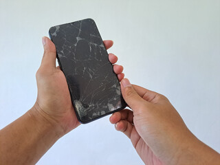 Hand's man holding black smartphone with a broken screen isolated on white background