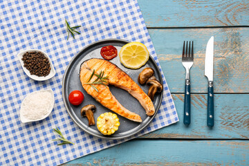 Plate with tasty grilled salmon steak on blue wooden background