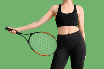 Young woman in sportswear and with tennis racket on green background