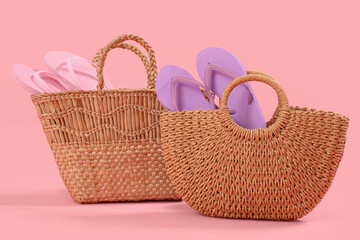 Wicker beach bags with flip-flops on pink background