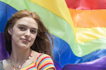 caucasian young woman with gay pride flag waving behind her