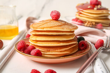 Plate of tasty pancakes with raspberries on white table