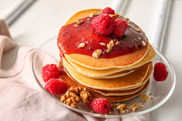 Plate of tasty pancakes with raspberries and nuts on white wooden background
