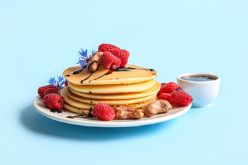 Plate of tasty pancakes with raspberries and nuts on blue background