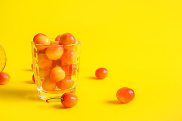 Cup with sweet yellow cherries on yellow background