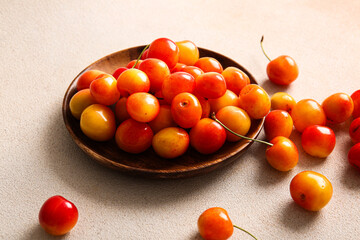 Plate with sweet yellow cherries on white background