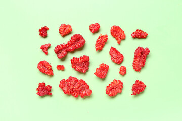 Pieces of fresh raspberries on green background