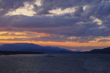 Sunset with pink, orange and purple sky above Inside Passage in British Columbia, Canada seen from cruiseship cruise ship liner returning from Alaska with mountains, shore and coast line