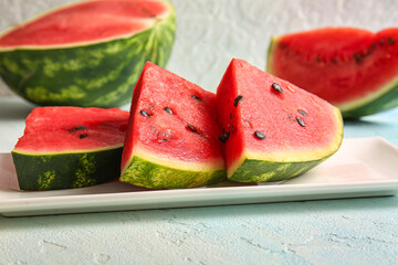 Plate with pieces of fresh watermelon on light blue table
