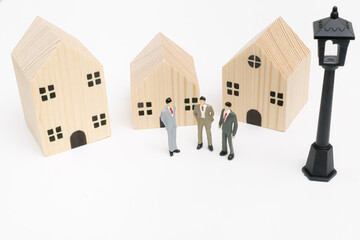 Three miniature businessman standing in front of wooden house for discuss about real estate investment, financial, purchase a new house. savings, economy, business, investment, loan, mortgage concept.