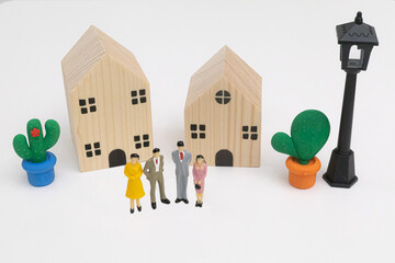 A miniature businessman standing in front of wooden house for discuss about real estate investment,...