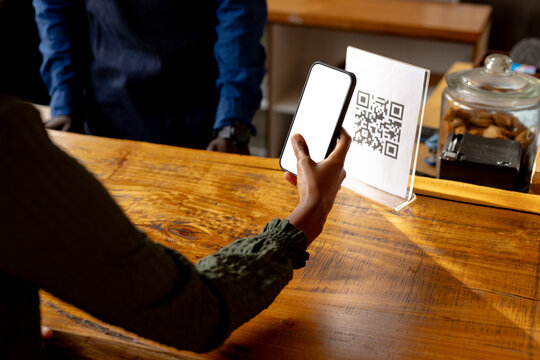 Hand of african american woman scanning qr code using smartphone in cafe - Powered by Adobe