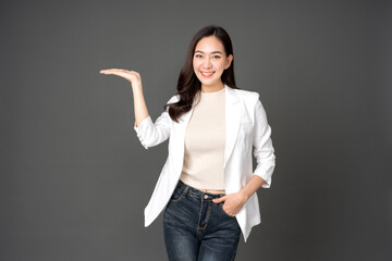 Asian female executive with long hair Posing with hands to present something Wearing a white suit...