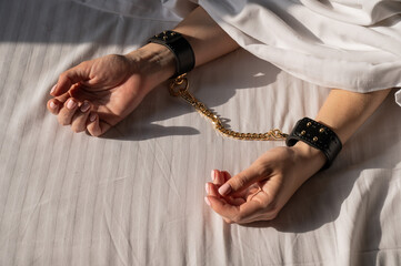 Close-up of woman's hands in leather handcuffs. Sex toy.