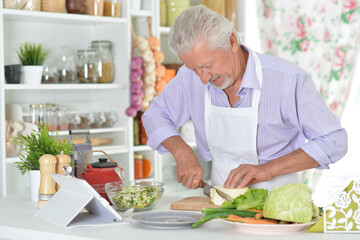 Portrait of senior man preparing dinner in kitchen