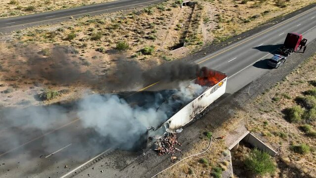 Aerial semi truck trailer fire desert highway climb pull. Interstate highway in desert of Arizona and Nevada. Transporting fresh meat. Fire and smoke destroys cargo and HAZMAT pollution.