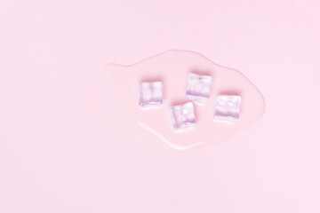Pink background with puddle of strawberry milkshake with fresh ice.