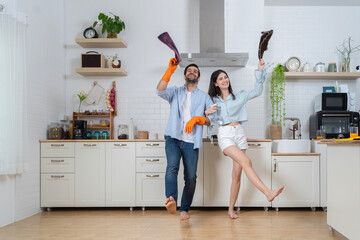 Cheerful young men and women imitate rock stars while taking care of the house. Happy young couple