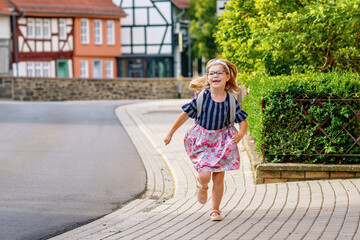 Little Preschool Girl on the Way to School. Healthy Happy Child Walking to Nursery School and Kindergarten. Smiling Child with Eyeglasses and Backpack on the City Street, Outdoors. Back to School.