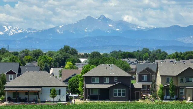 New upscale housing development in Colorado. Aerial truck shot of houses and homes with snow capped Rocky Mountains in distance. Long zoom lens. Population growth theme.
