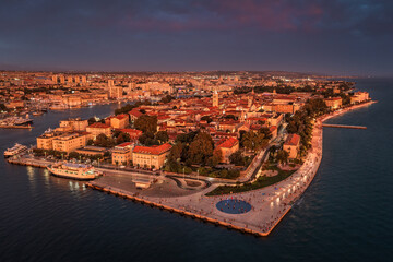 Zadar, Croatia - Aerial panoramic view of golden glowing old town of Zadar with the greeting to the sun monument, sea organ, dramatic sunset lights on a beautiful summer afternoon in Dalmatia