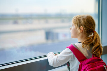 Little Girl at the Airport Waiting for Boarding at the Big Window. Cute Kid Stands at the Window...