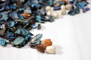 A mix of dry flowers, leaves, petals, and other plant parts. Potpourri background. Purple and blue tone leaves, white color and wood grain background shot.