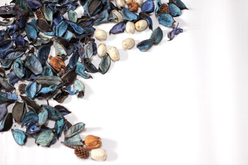 A mix of dry flowers, leaves, petals, and other plant parts. Potpourri background. Purple and blue tone leaves, white color and wood grain background shot.