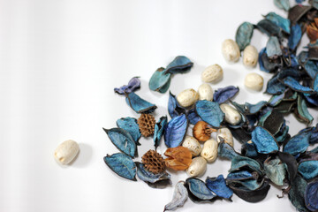 A mix of dry flowers, leaves, petals, and other plant parts. Potpourri background. Purple and blue tone leaves, white color and wood grain background shot.