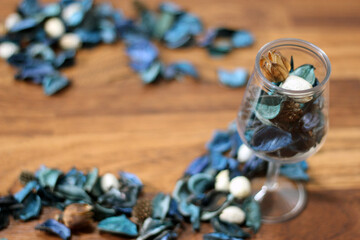 A mix of dry flowers, leaves, petals, and other plant parts. Potpourri background. Purple and blue tone leaves, white color and wood grain background shot.