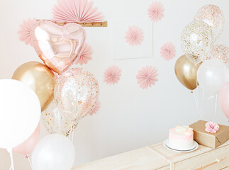 Birthday celebration for girl at home light pink and gold colors. cake with flowers, balloons, gift