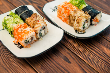 Several sushi on a white plate standing on a brown background
