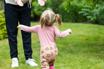 toddler girl runs to her mother, summer outdoors