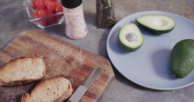 Close up of sliced bread, avocado and spices in kitchen, slow motion