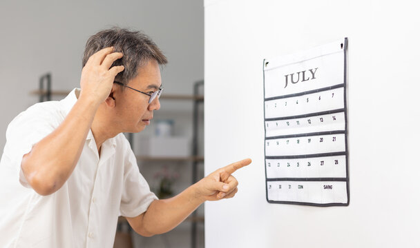 Confused Asian Senior Man With Dementia Looking At Wall Calendar