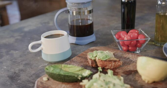 Close up of avocado sandwiches, vegetables and coffee in kitchen, slow motion