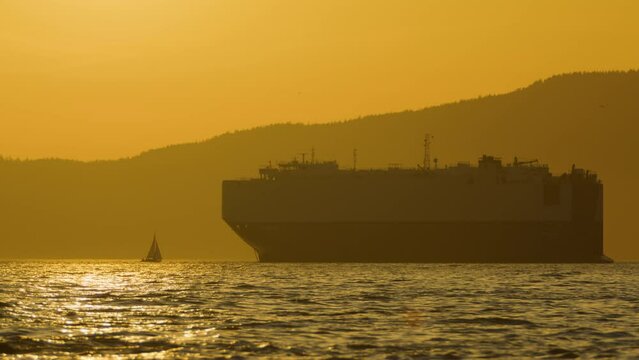 Silhouetted Cargo Ship and Small Sailboat in Vancouver English Bay - Sunset Sky