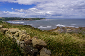 View from the Cleveland Way. This clifftop view is seen as you walk north approaching Kettleness, at the other side of the bay is the seaside village of Runswick Bay.