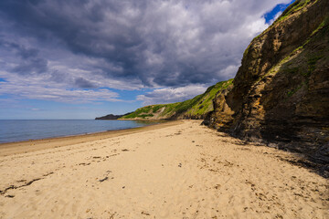 Runswick Bay beach and its pristine sandy beach exposed at low tide. A line of cliffs provide a...