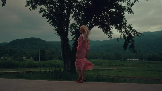 Woman in a vintage dress and red shoes walking down the road