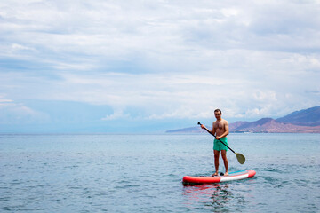 Fototapeta na wymiar A man on a surfboard with a paddle