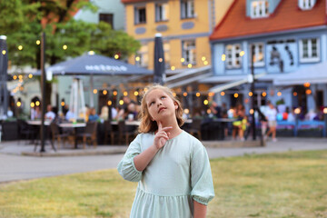 Summer portrait of a girl in a beautiful dress. walking along the beautiful streets of the old city in Riga. Evening lighting, cafes on the streets, flags  Lithuania and Ukraine. Travel,tourism, walks - obrazy, fototapety, plakaty