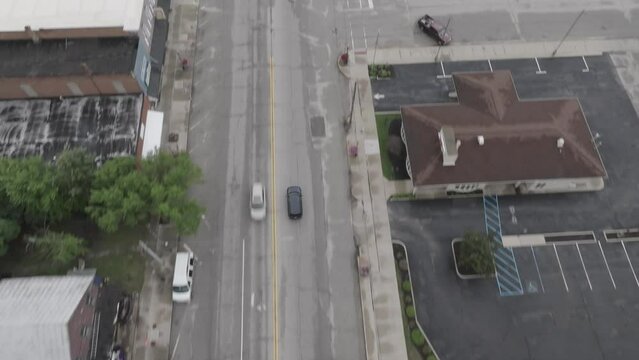 Downtown Elkhart, Indiana with cars driving and drone video tilting up.