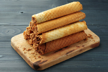 Waffle tubes with chocolate filling on wooden board