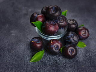 Sweet plums on dark background. Fresh blue plums with leaves. Food fruit Background. Summer postcard. Harvesting in garden, Harvest of plum