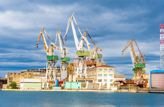 cargo sea port with cranes vehicles, container stacks , supplies and trucks with goods, sea hub terminal from seashore