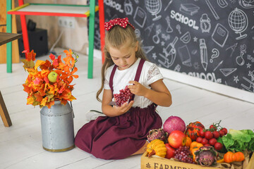 Little cute schoolgirl sitting in the classroom. Studying. Fruits and vegetables. Education. Childhood concept.