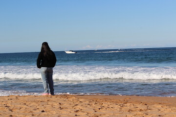 Woman in facing back looking at the sea standing on a beach